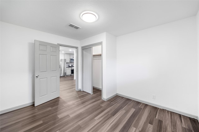 9211 Helmers St, Houston, TX 77022 - unfurnished bedroom with freestanding refrigerator, visible vents, wood finished floors, and baseboards