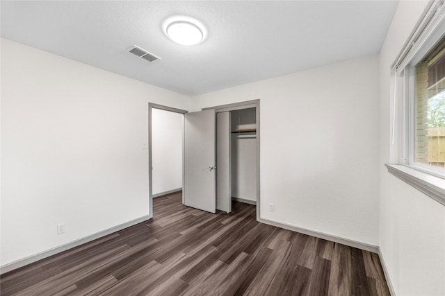 9211 Helmers St, Houston, TX 77022 - unfurnished bedroom with a closet, dark wood finished floors, visible vents, and baseboards