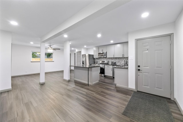9211 Helmers St, Houston, TX 77022 - kitchen featuring ceiling fan, decorative backsplash, wood finished floors, dark countertops, and appliances with stainless steel finishes