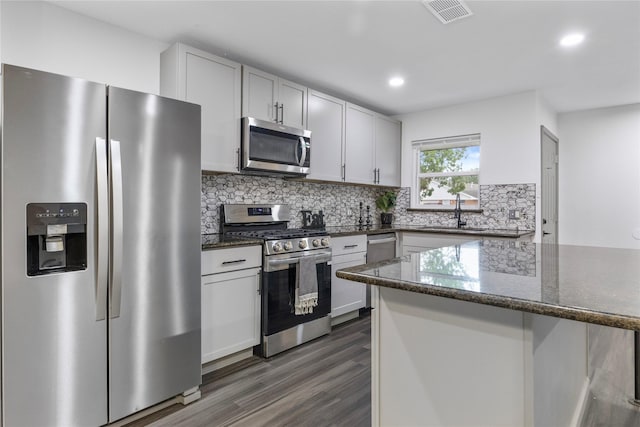 9211 Helmers St, Houston, TX 77022 - kitchen with a sink, stainless steel appliances, visible vents, dark wood-type flooring, and tasteful backsplash