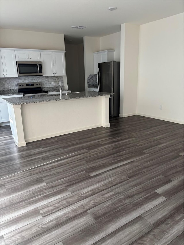5811 Capri Forest Dr, Katy, TX 77493 - kitchen with stainless steel appliances, an island with sink, white cabinets, and dark stone counters