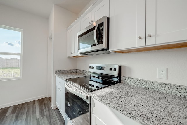 5811 Capri Forest Dr, Katy, TX 77493 - kitchen featuring appliances with stainless steel finishes, white cabinets, wood finished floors, light stone counters, and baseboards