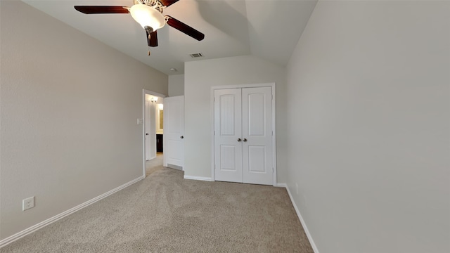 unfurnished bedroom with lofted ceiling, a closet, light colored carpet, visible vents, and baseboards