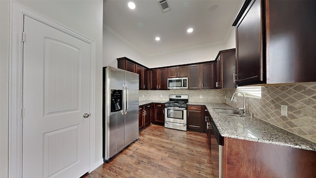 kitchen featuring a sink, stainless steel appliances, visible vents, light stone countertops, and ornamental molding