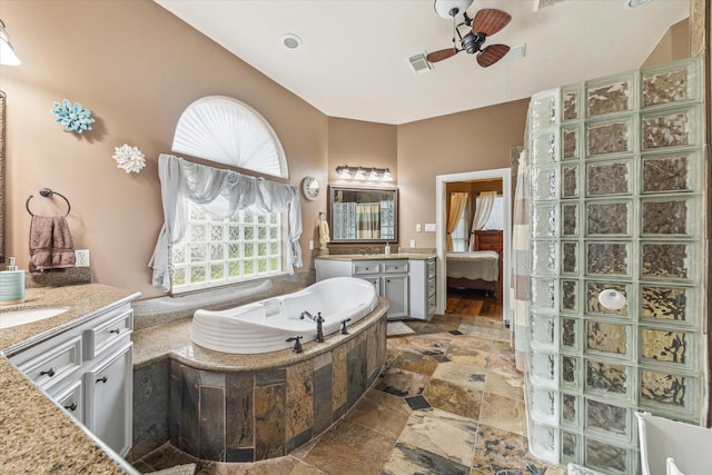 bathroom with stone tile flooring, ceiling fan, plenty of natural light, and a bath