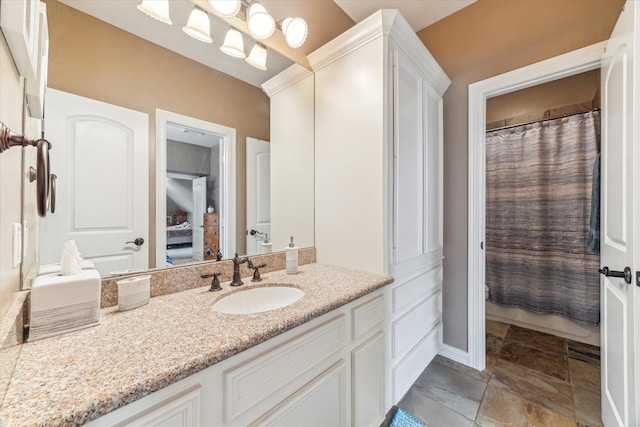 bathroom featuring vanity, stone tile floors, and baseboards