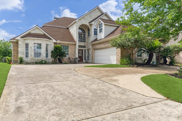 traditional-style home with concrete driveway, stone siding, a shingled roof, a garage, and brick siding