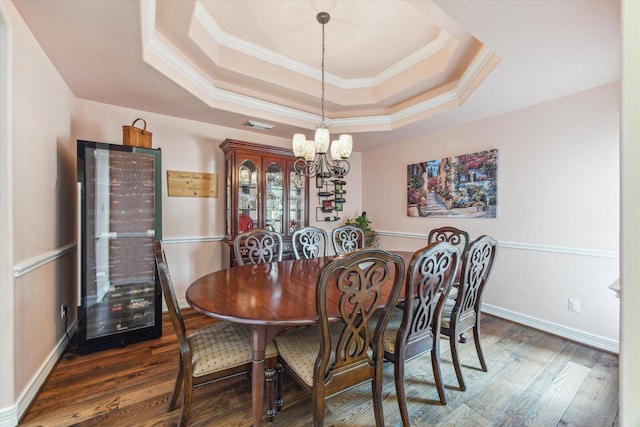 dining area with a chandelier, ornamental molding, wood finished floors, a raised ceiling, and baseboards