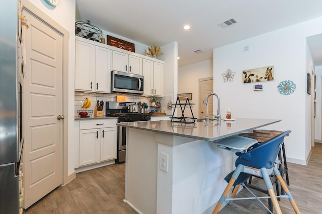 1830 William Scott St, Baytown, TX 77523 - kitchen with light wood-style flooring, a sink, white cabinetry, decorative backsplash, and stainless steel appliances
