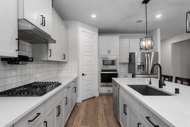 17828 Hanson Ridge Dr, Conroe, TX 77316 - kitchen with appliances with stainless steel finishes, under cabinet range hood, a sink, light countertops, and recessed lighting