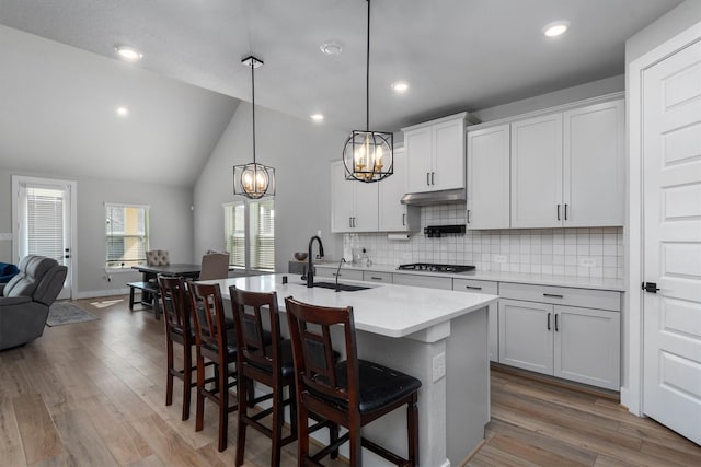 17828 Hanson Ridge Dr, Conroe, TX 77316 - kitchen featuring stainless steel gas cooktop, a sink, a chandelier, open floor plan, and a kitchen island with sink