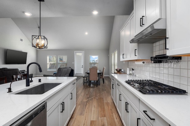 17828 Hanson Ridge Dr, Conroe, TX 77316 - kitchen with a sink, under cabinet range hood, lofted ceiling, open floor plan, and light countertops