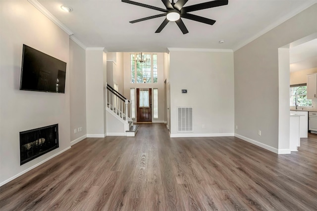 17422 Marigold Dr, Sugar Land, TX 77479 - unfurnished living room featuring stairs, crown molding, wood finished floors, a ceiling fan, and a chandelier