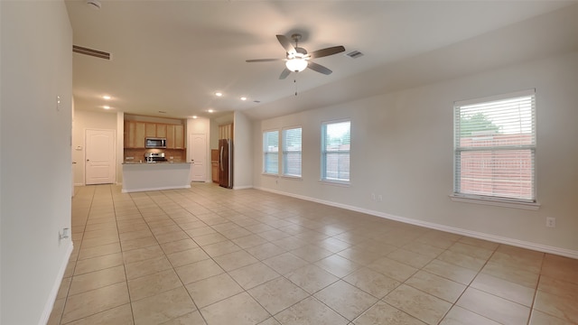 unfurnished living room with light tile patterned floors, visible vents, baseboards, and ceiling fan