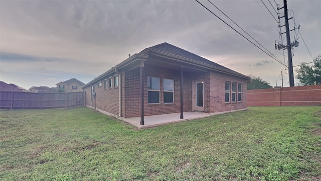 back of house featuring brick siding, a lawn, a fenced backyard, and a patio