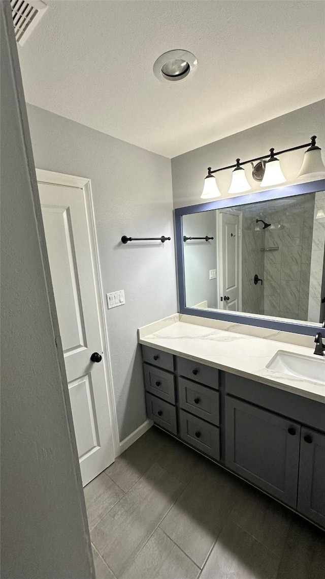 407 Bendwood Dr Unit 38, Houston, TX 77024 - full bathroom featuring vanity, visible vents, tile patterned floors, baseboards, and tiled shower