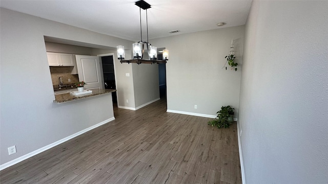 407 Bendwood Dr Unit 38, Houston, TX 77024 - unfurnished dining area featuring baseboards, an inviting chandelier, visible vents, a sink, and wood finished floors