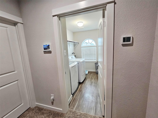 washroom featuring wood finished floors, laundry area, baseboards, a textured wall, and independent washer and dryer