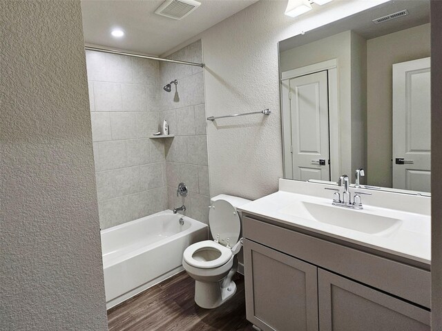 full bath featuring toilet, a textured wall, visible vents, and wood finished floors