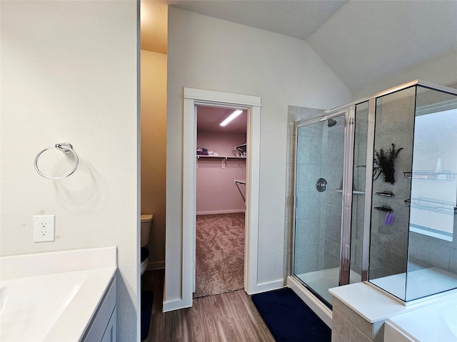 bathroom featuring toilet, a spacious closet, a shower stall, and wood finished floors