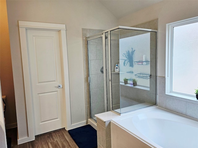 bathroom featuring a stall shower, a bath, and wood finished floors