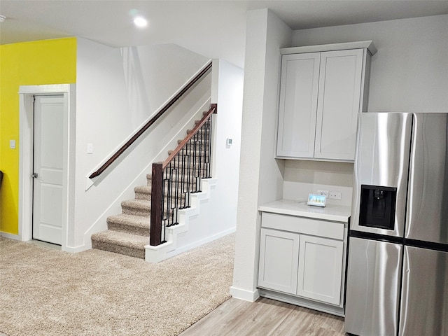 kitchen featuring stainless steel fridge, light countertops, light wood-style floors, and baseboards