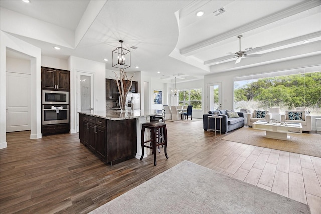 3419 Campestres, Spring Branch, TX 78070 - kitchen featuring a kitchen bar, stainless steel appliances, open floor plan, dark brown cabinetry, and dark wood finished floors