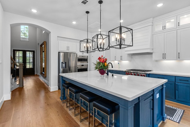 203 S Empress Green Pl, Montgomery, TX 77316 - kitchen featuring arched walkways, light countertops, visible vents, and blue cabinets