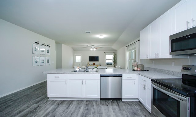 18715 Callalily Bloom Ct, Tomball, TX 77377 - kitchen featuring a sink, a peninsula, light wood-type flooring, open floor plan, and appliances with stainless steel finishes