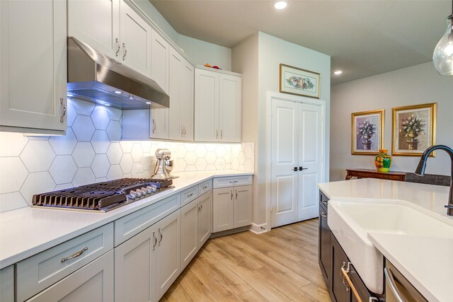 9823 Starry Night Ln, Manvel, TX 77578 - kitchen with a sink, stainless steel appliances, under cabinet range hood, light countertops, and light wood-style floors