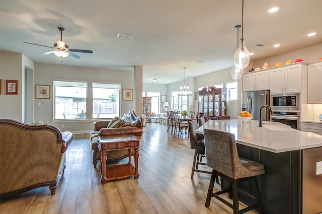 9823 Starry Night Ln, Manvel, TX 77578 - kitchen featuring ceiling fan with notable chandelier, open floor plan, visible vents, light countertops, and appliances with stainless steel finishes