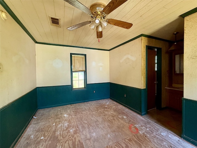 unfurnished room featuring a wainscoted wall, visible vents, and a ceiling fan