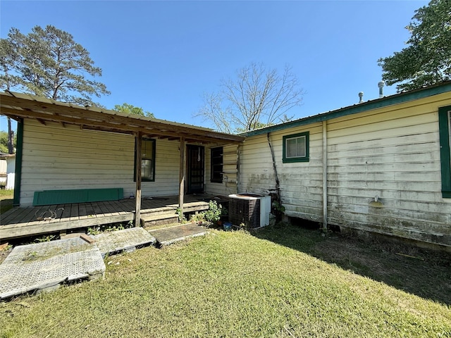 rear view of property featuring cooling unit, a yard, and a deck