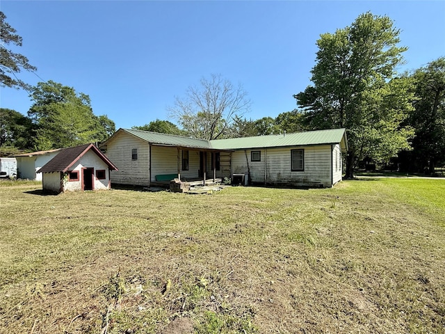 rear view of house featuring a yard, metal roof, and a shed