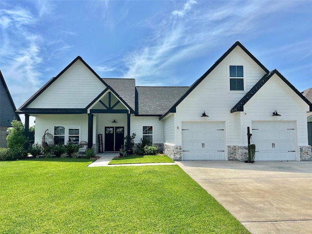 view of front of house with a garage, a shingled roof, concrete driveway, stone siding, and a front lawn