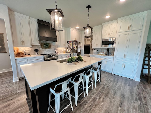 kitchen with a sink, appliances with stainless steel finishes, tasteful backsplash, custom range hood, and recessed lighting