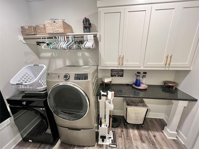 washroom with baseboards, washing machine and dryer, cabinet space, and wood finished floors
