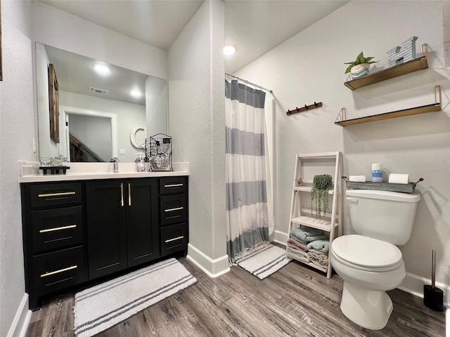 bathroom featuring toilet, baseboards, visible vents, and wood finished floors