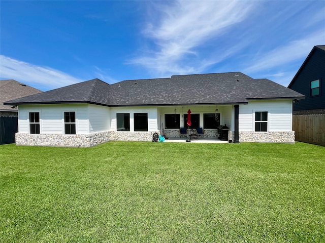 rear view of house featuring a yard, roof with shingles, fence, and a patio
