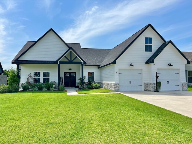 view of front facade featuring roof with shingles, an attached garage, a front lawn, and driveway