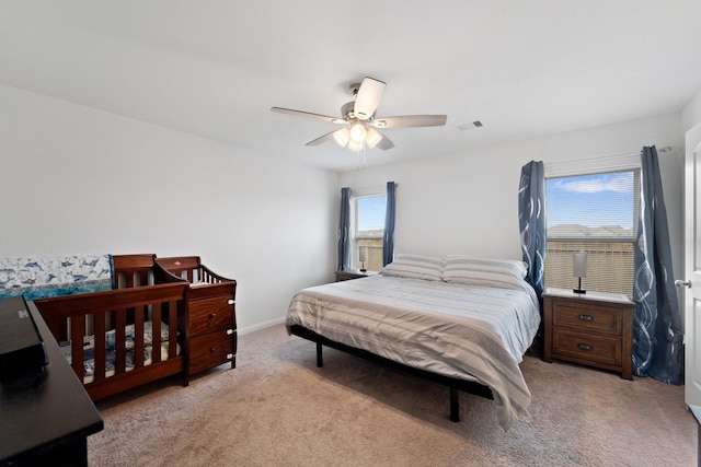 bedroom featuring baseboards, ceiling fan, light carpet, and visible vents