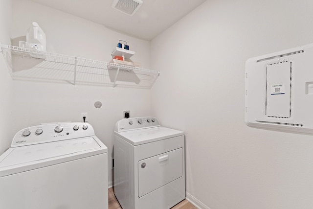 clothes washing area featuring light wood-style flooring, laundry area, visible vents, and independent washer and dryer