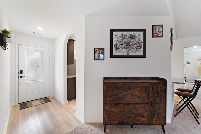 entryway featuring light wood-type flooring, visible vents, baseboards, arched walkways, and recessed lighting