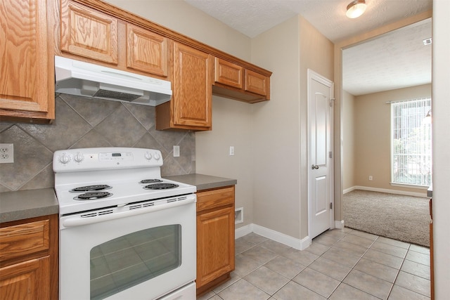 24006 Lestergate Dr, Spring, TX 77373 - kitchen featuring tasteful backsplash, baseboards, under cabinet range hood, light tile patterned floors, and white range with electric stovetop