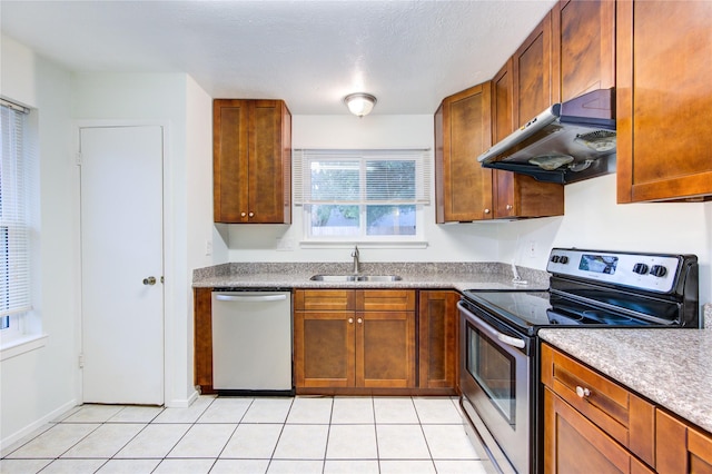 kitchen featuring a sink, brown cabinetry, stainless steel appliances, light tile patterned flooring, and under cabinet range hood