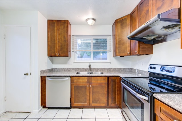 kitchen with under cabinet range hood, appliances with stainless steel finishes, light tile patterned flooring, and a sink