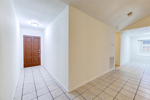 corridor with vaulted ceiling, visible vents, and light tile patterned flooring