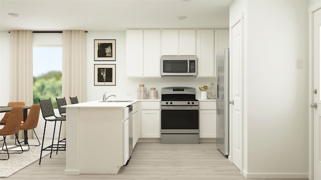 kitchen with appliances with stainless steel finishes, a sink, white cabinets, a peninsula, and light wood-style floors