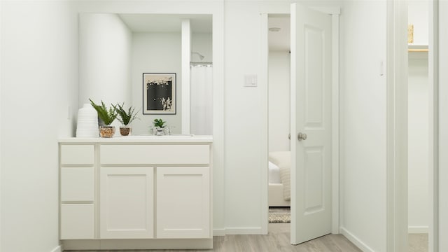 hall featuring a sink, baseboards, and light wood-style floors
