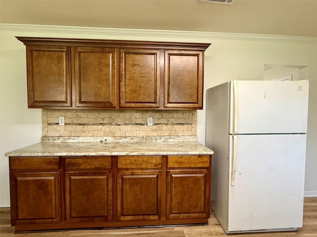 602 E Main St, Kirbyville, TX 75956 - kitchen featuring light wood finished floors, freestanding refrigerator, crown molding, visible vents, and tasteful backsplash